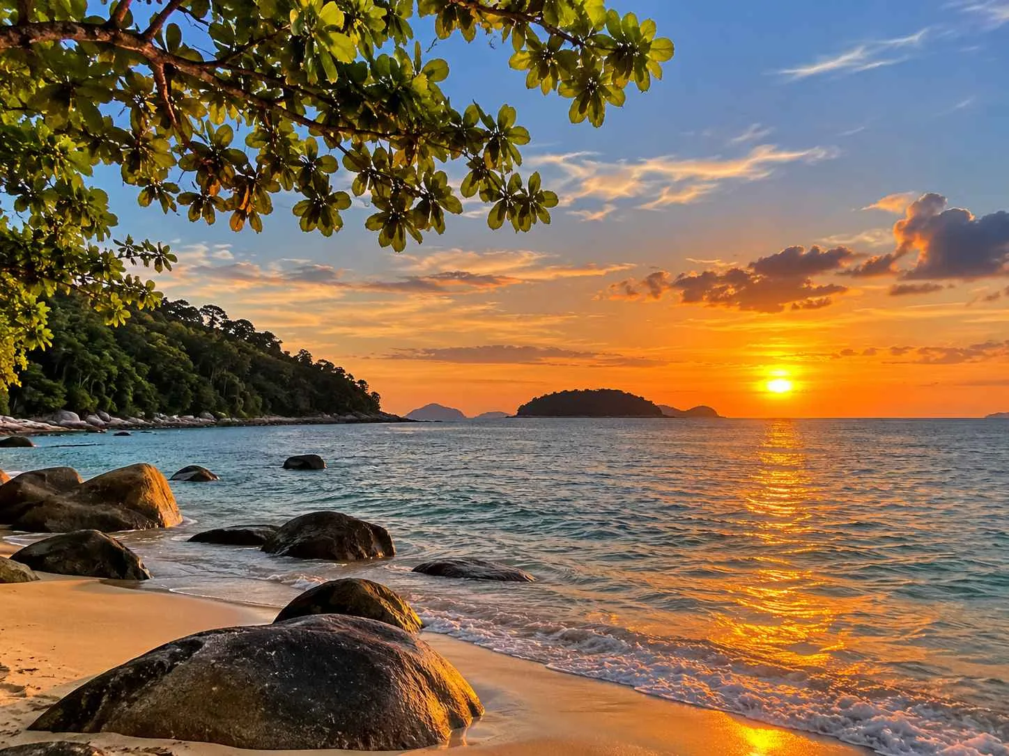 Sunset over the western coastline of Pangkor Island with sandy beach, sea and offshore island silhouettes